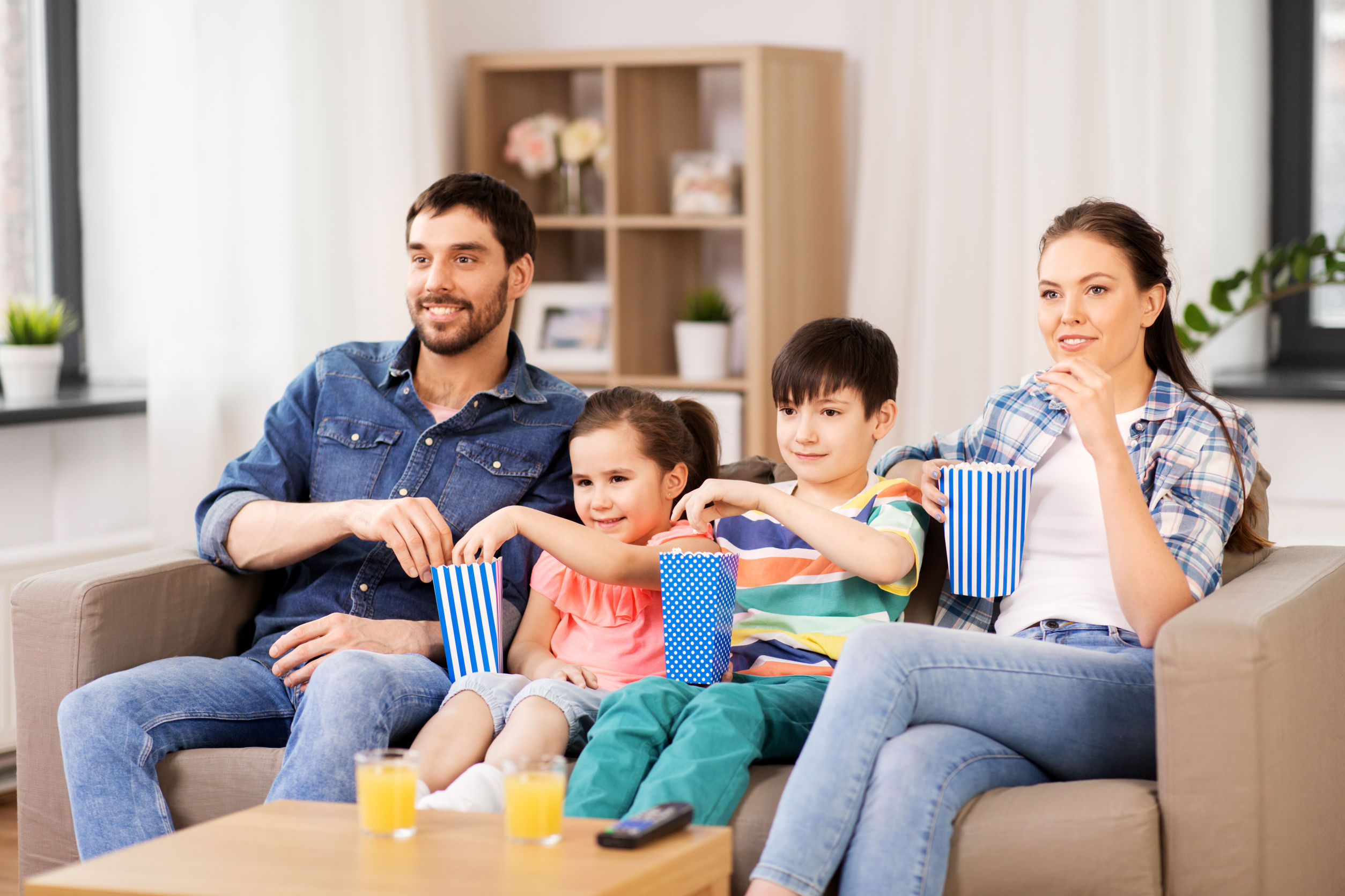 happy family with popcorn watching tv at home